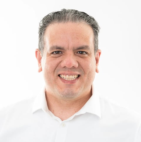Middle-aged man with gray hair smiling at camera wearing white collared shirt against white background